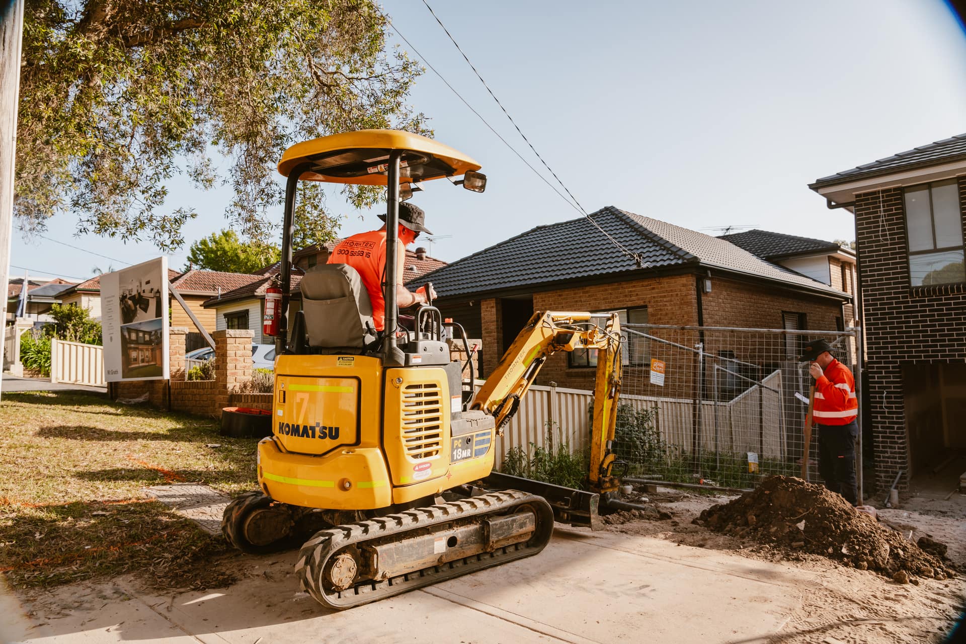 Thorntek excavator trenching a residential driveway for underground consumer mains in Sydney