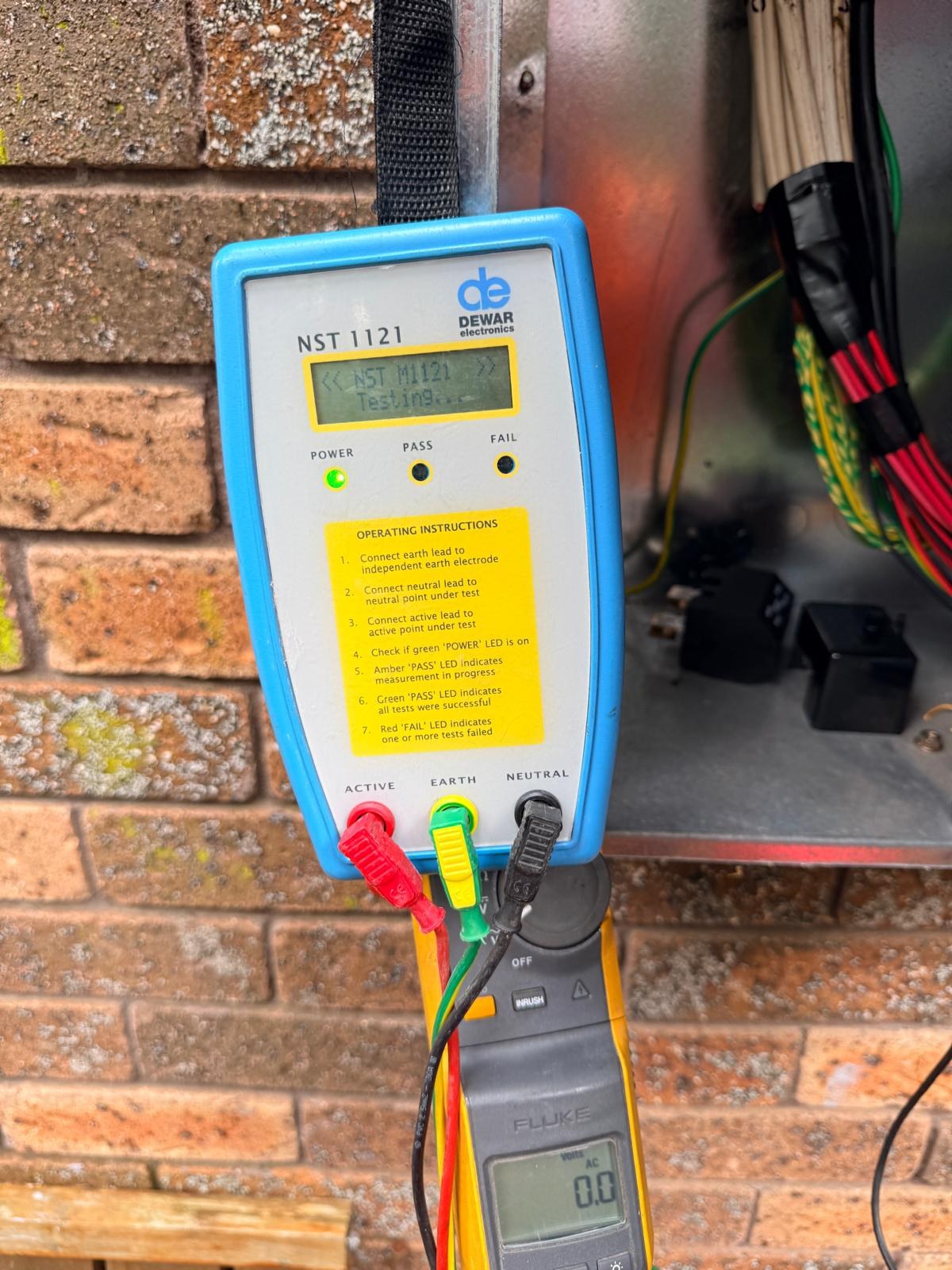 Neutral integrity tester and clamp meter in use at an open switchboard