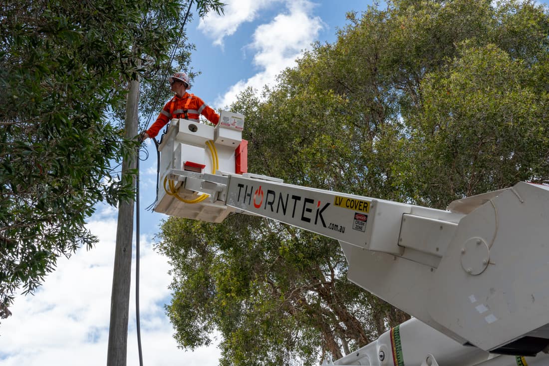 Thorntek elevated work platform lifting a technician to overhead service lines at a power pole