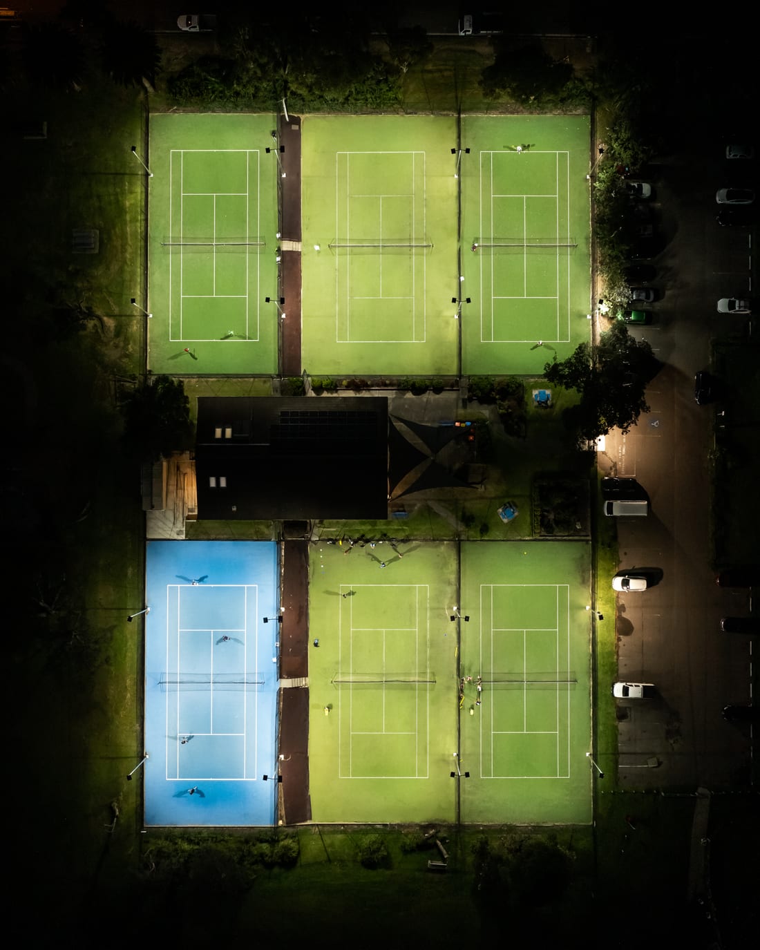Drone view from directly above the floodlit Collaroy tennis courts at night