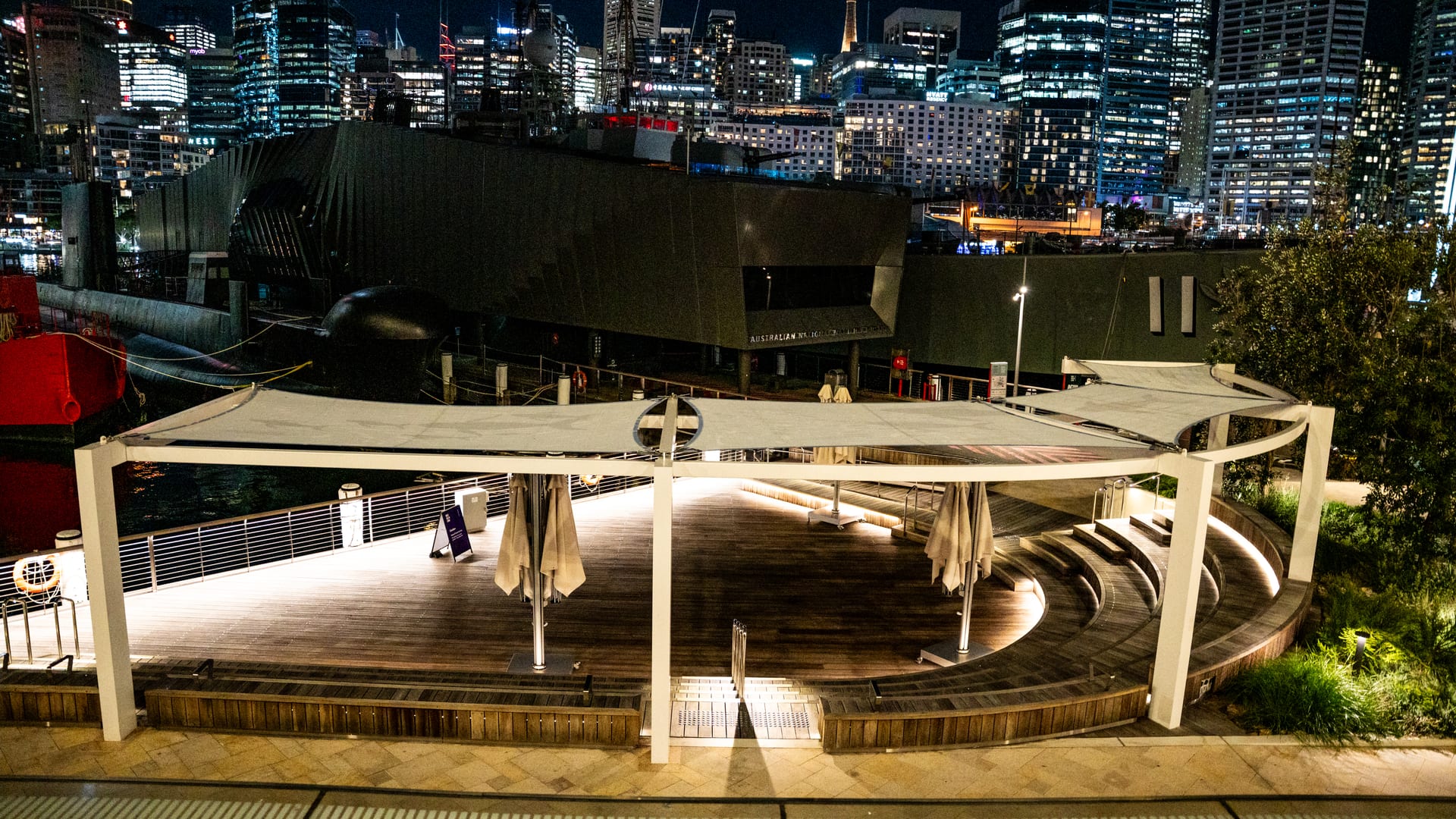 Floodlit harbour edge boardwalk and terrace at the Australian National Maritime Museum at night