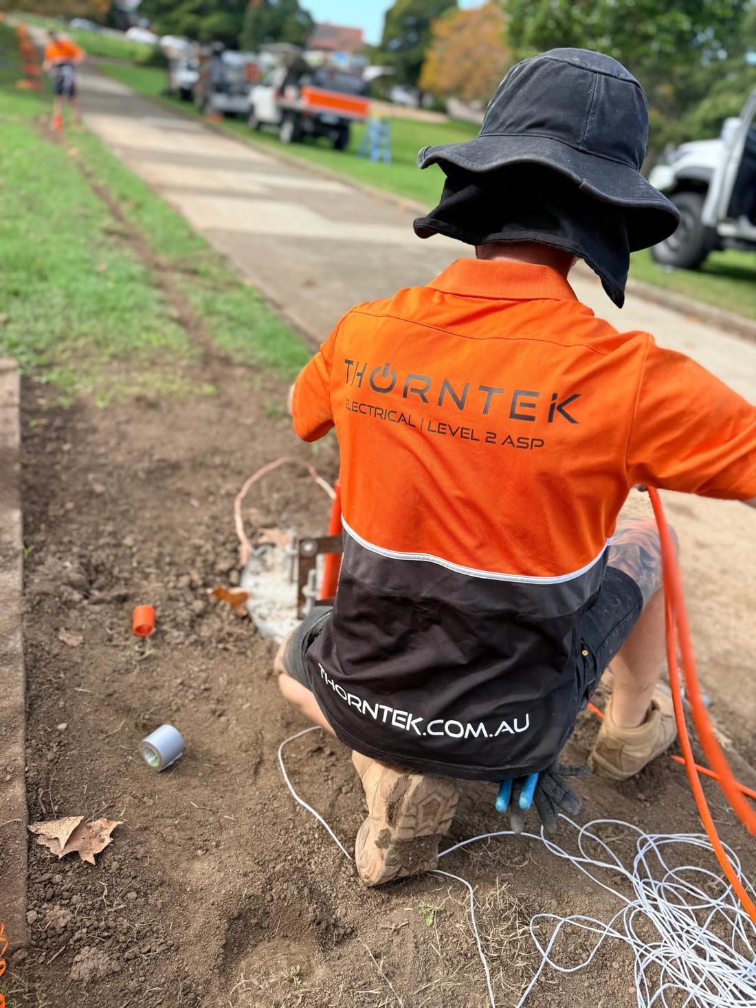 Thorntek electrician in branded shirt working at a kerbside cable pull