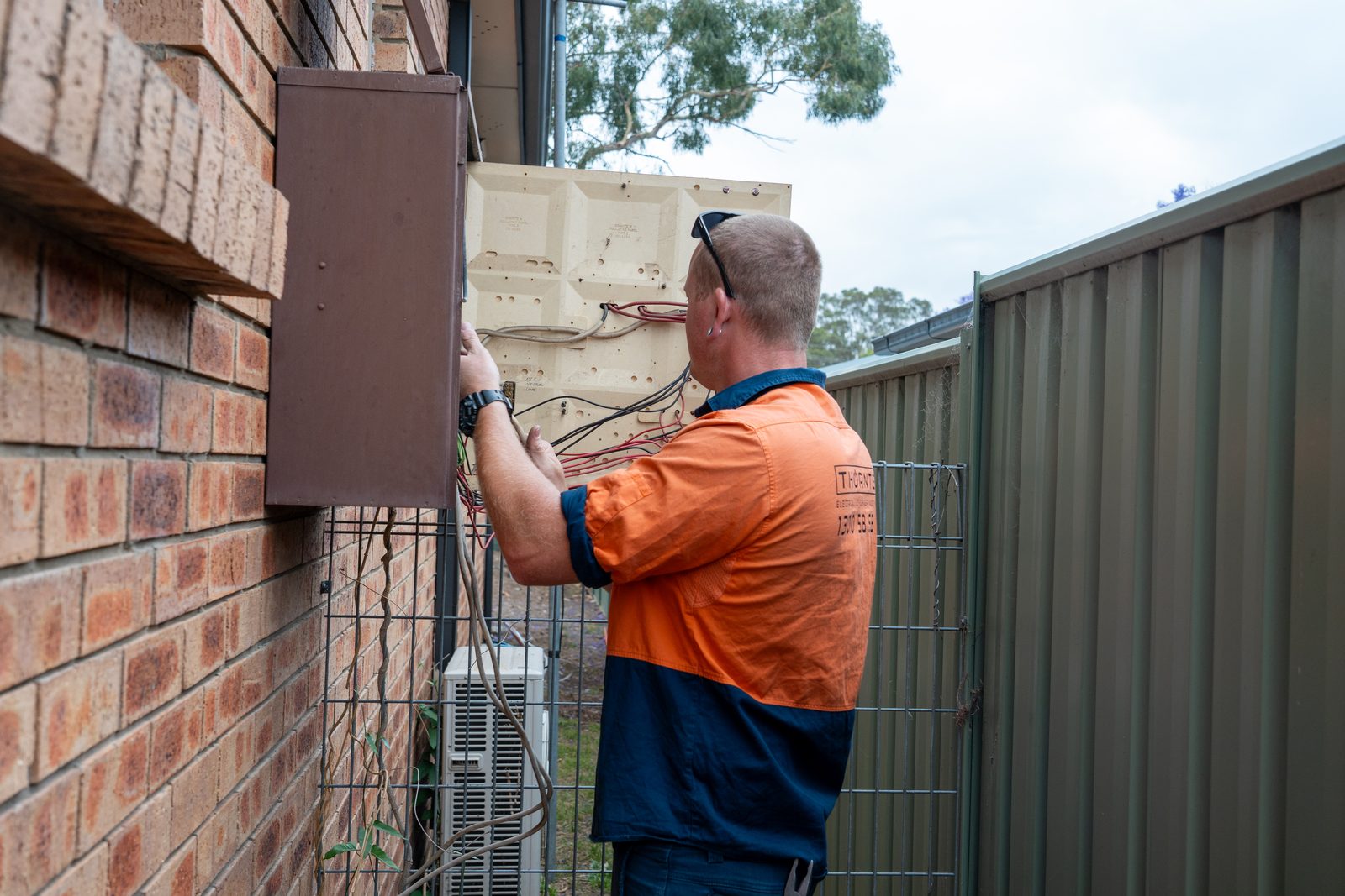 Electrician working inside an open residential meter box during a switchboard upgrade