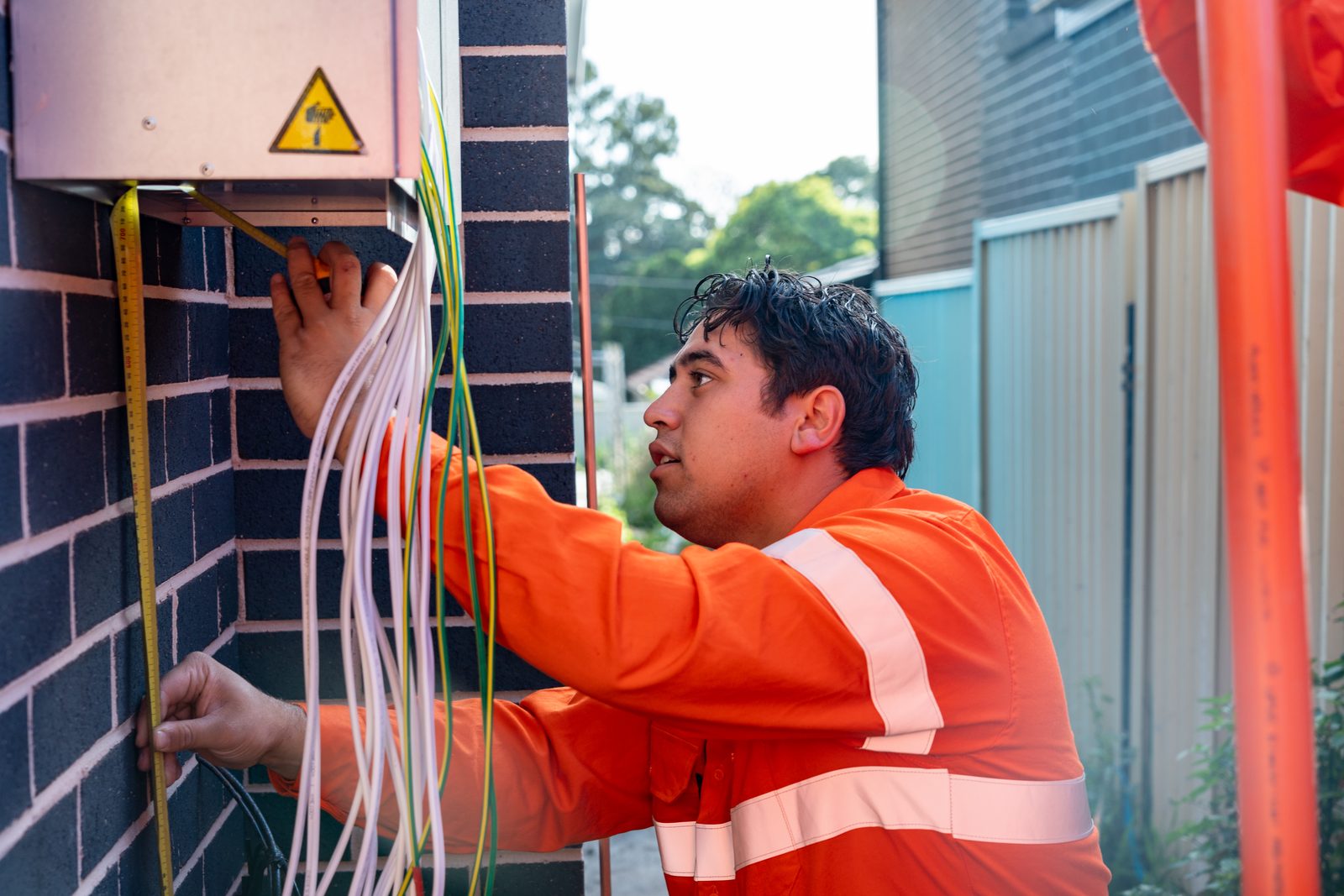 Thorntek electrician terminating cables beneath an electricity meter enclosure