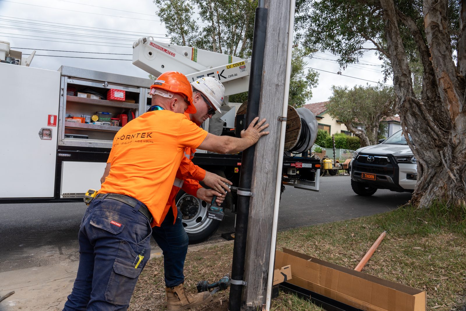 Thorntek electricians fixing a conduit riser to a timber private power pole