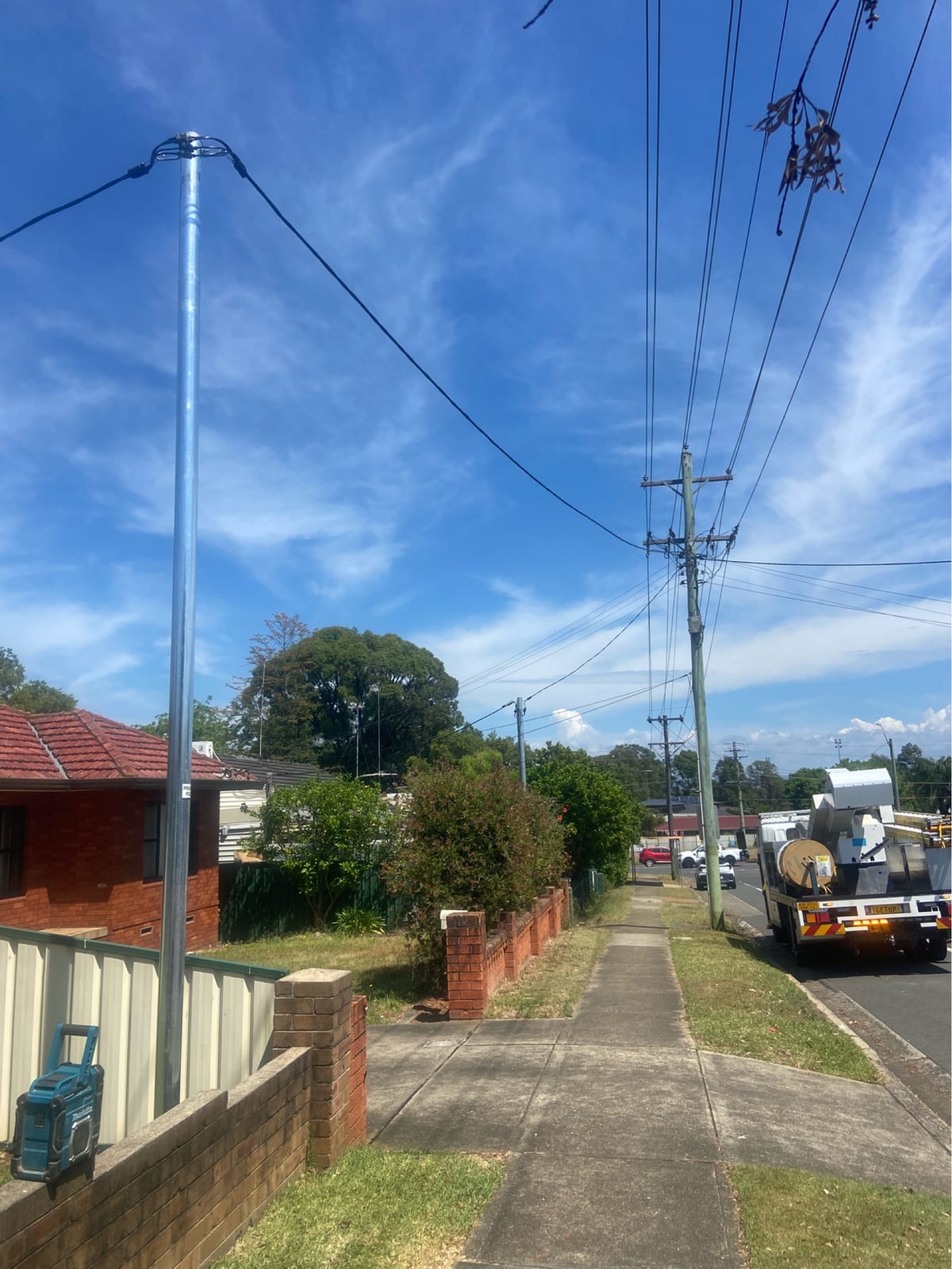 New steel private power pole at a front fence with the service span to the street pole, Thorntek truck down the road