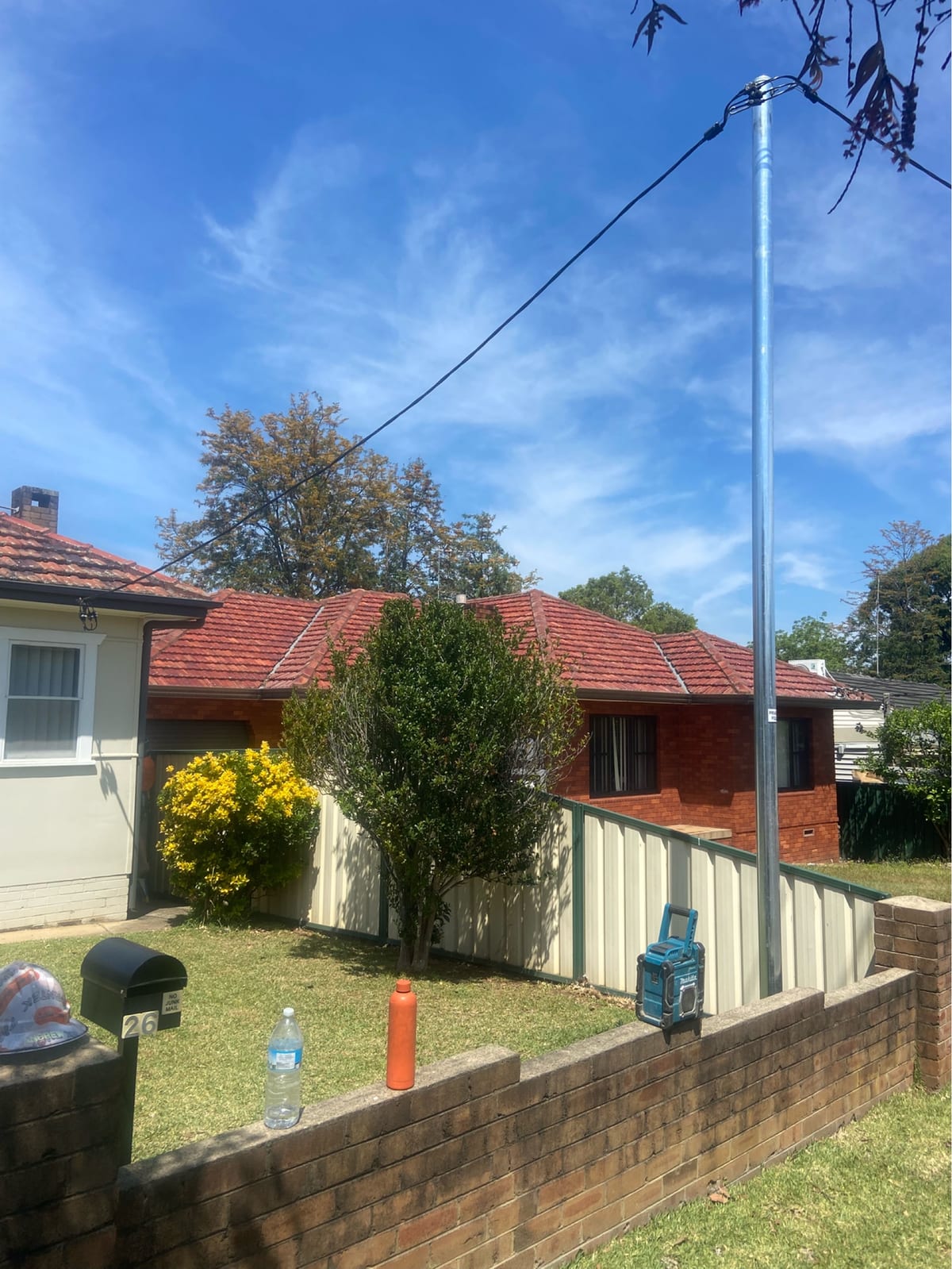New galvanised steel private power pole installed at the front of a brick home, service mains connected