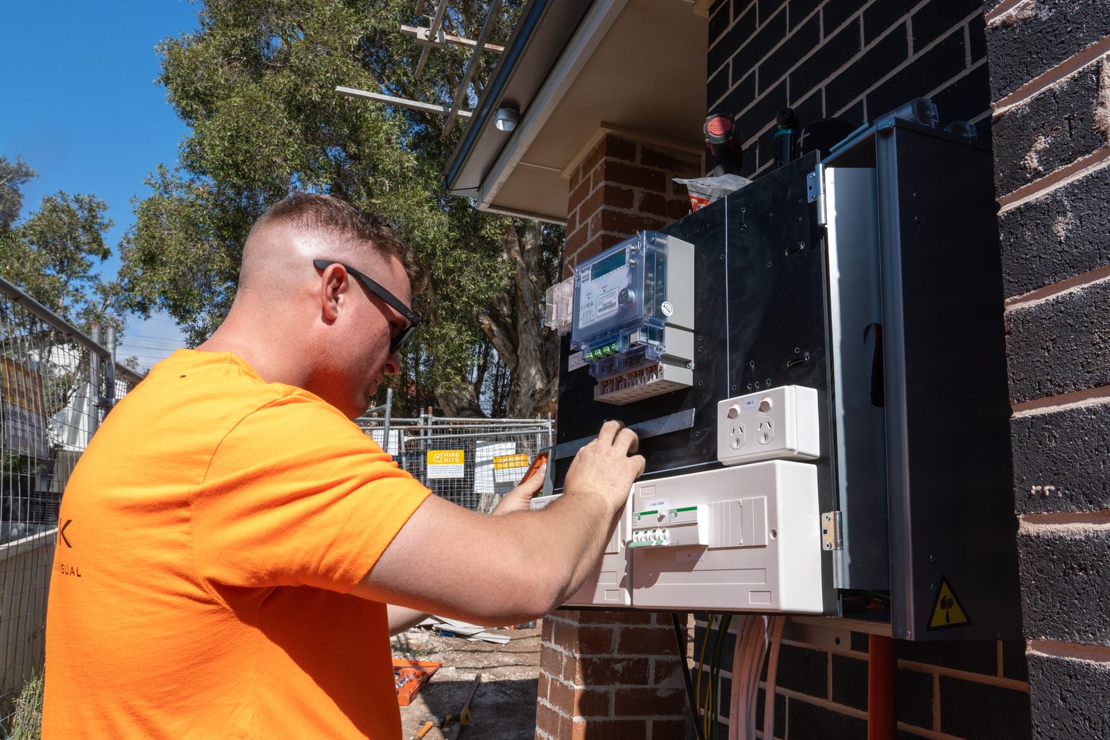 Thorntek electrician completing a new residential switchboard and smart meter installation on a brick home
