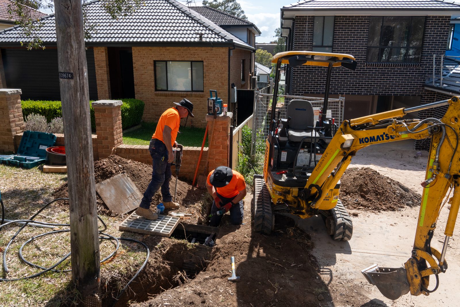 Thorntek crew and excavator trenching an underground service at a house frontage